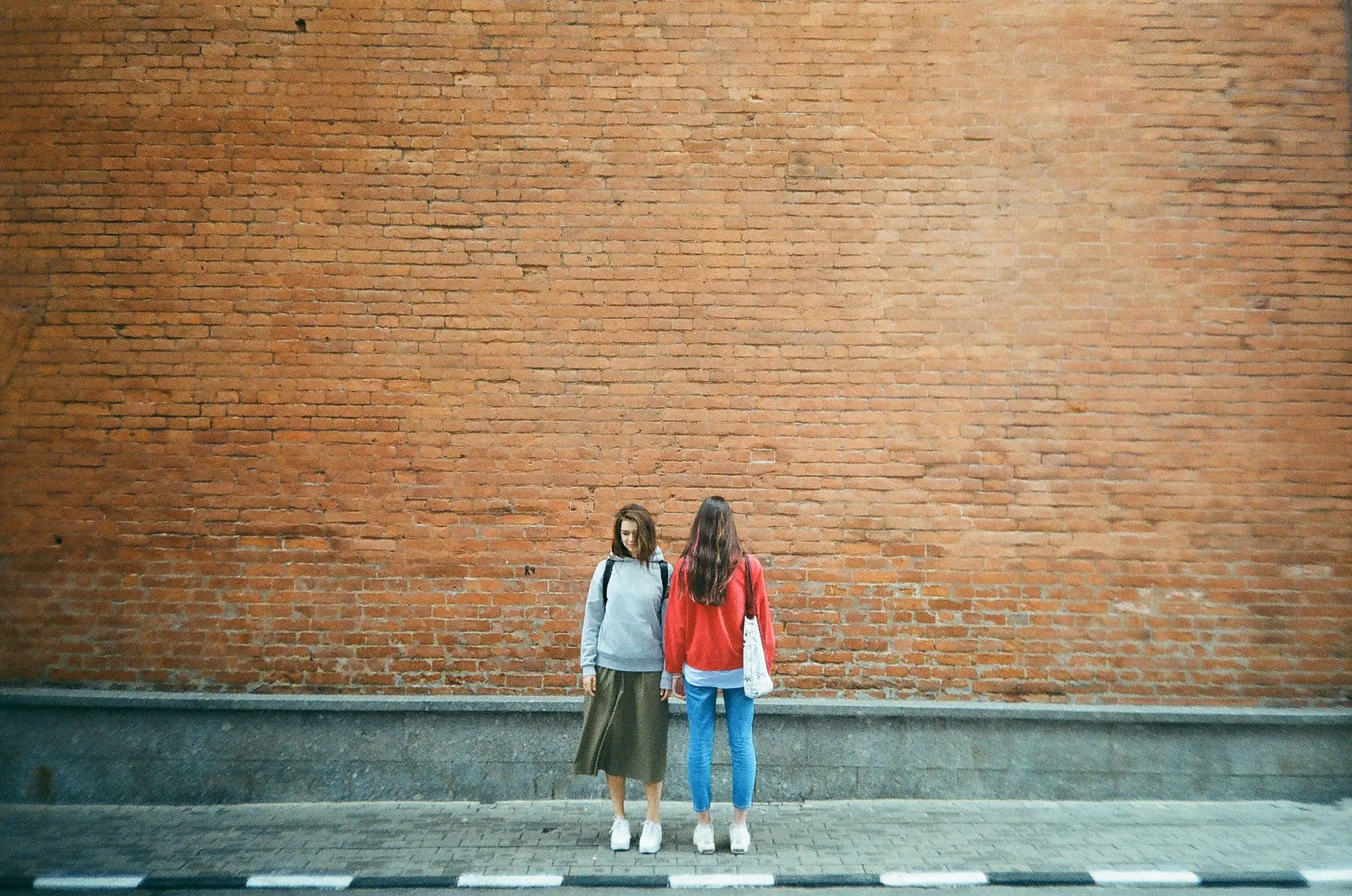 Two young women against a brick wall