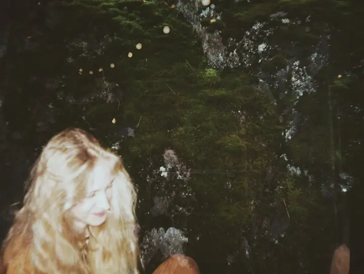 Blonde hair against dark woods
